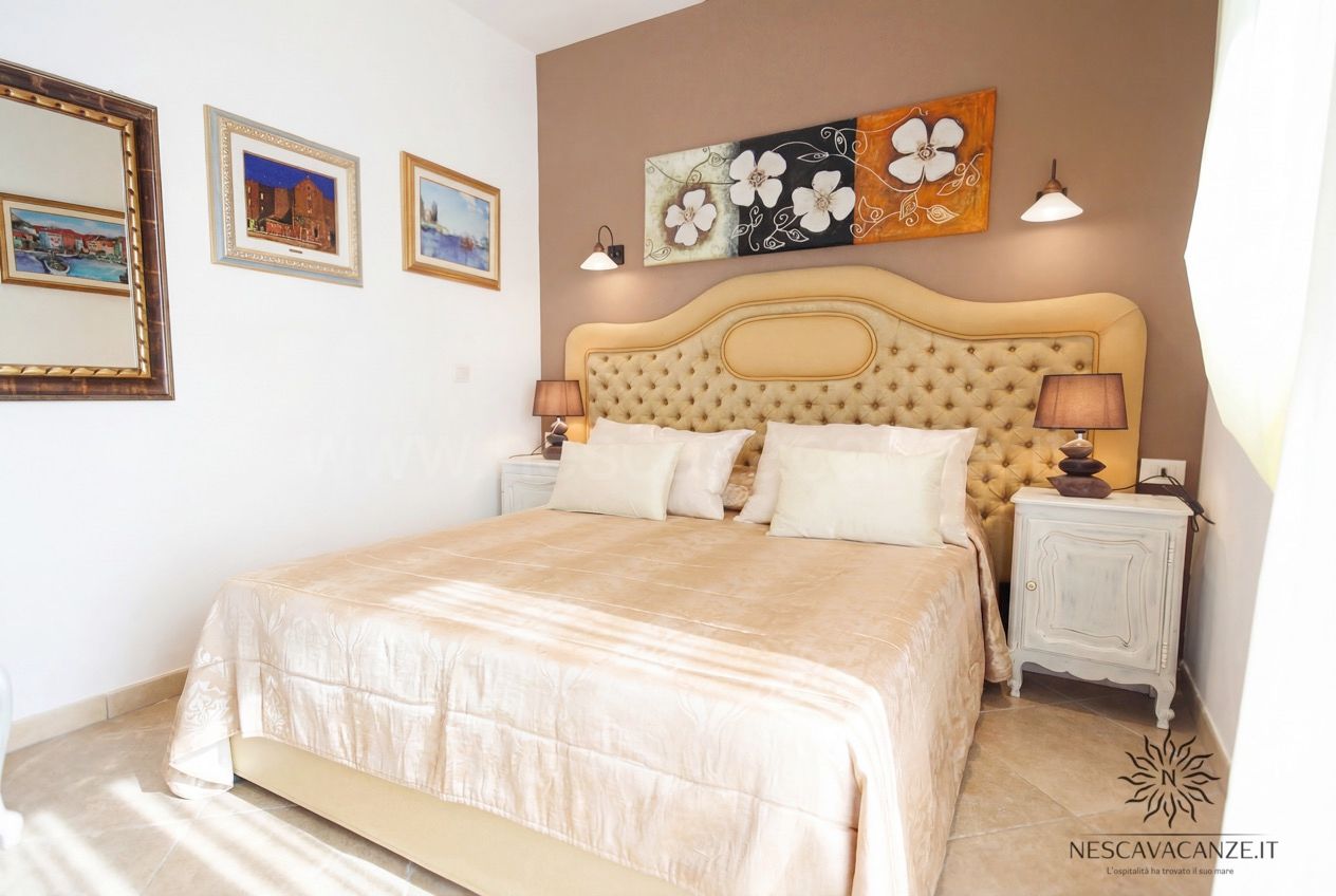 Casa Pescoluse 9 - camera matrimoniale con testiera capitonné, quadro floreale e lampade da comodino