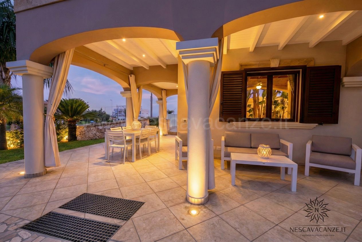 Casa Pescoluse 8 - Veranda illuminata al tramonto con salotto, tavolo da pranzo e colonne