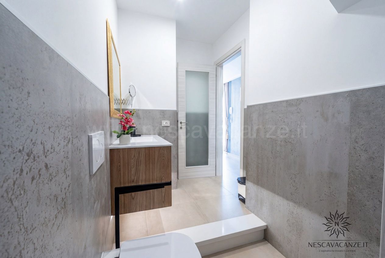 Casa Pescoluse 2 - bagno con mobile in legno, specchio dorato, pareti grigie e corridoio