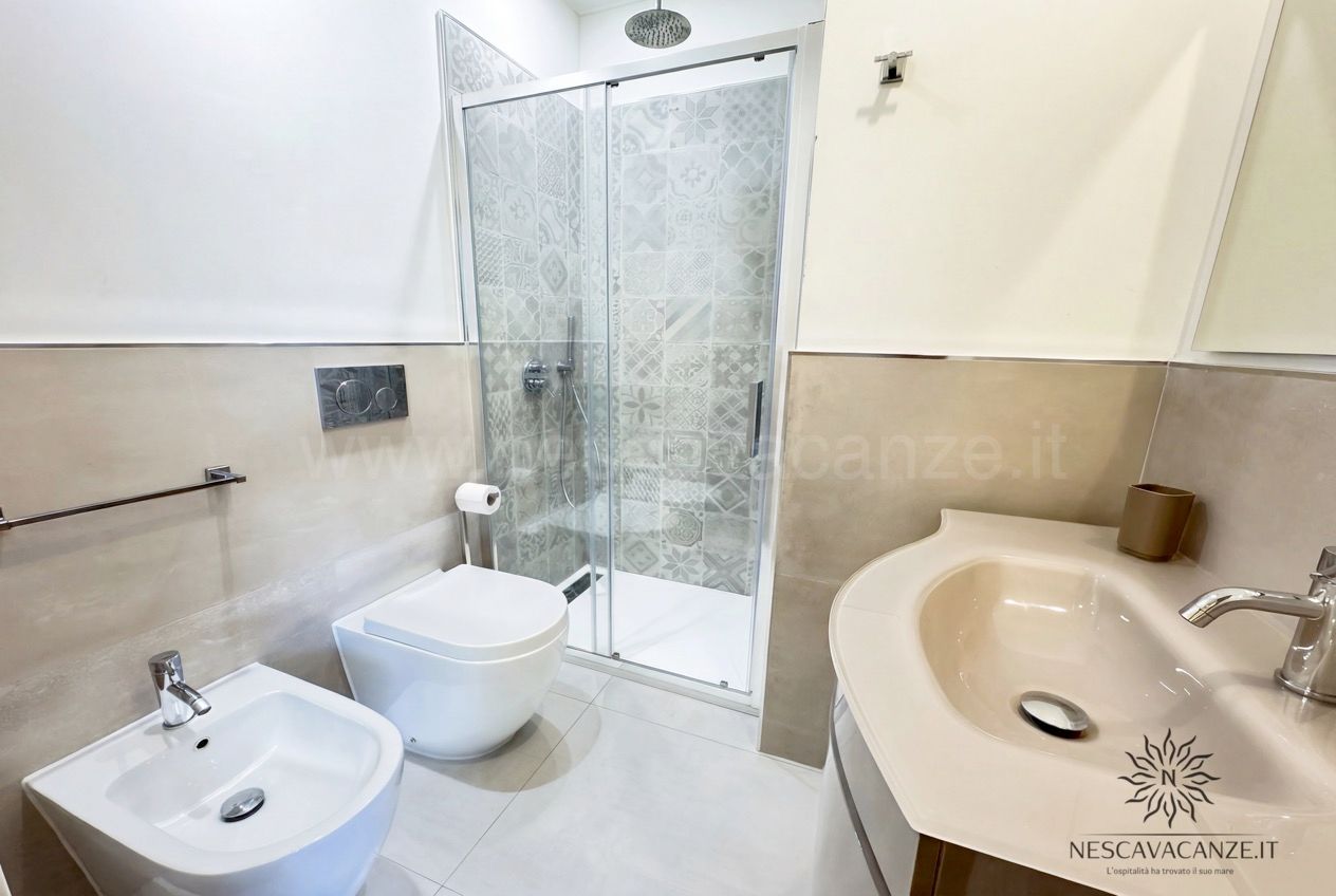 Casa Sabbia Oro - bagno con box doccia a mosaico, wc, bidet e lavabo curvo con specchio