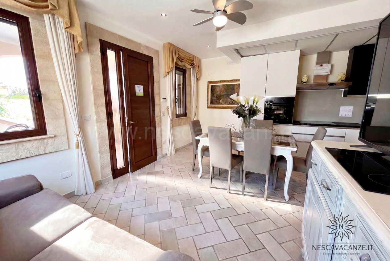 Casa Pescoluse 4 - angolo cottura bianco con piano cottura, tavolo da pranzo, divano e porta d'ingresso