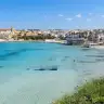 La spiaggia cittadina di Otranto con l'acqua trasparente e il centro storico sullo sfondo