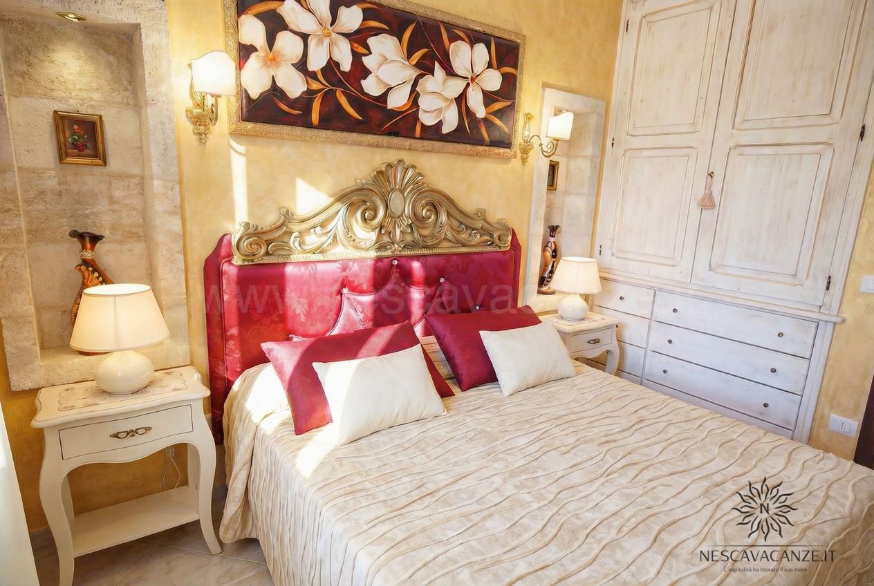 Casa Pescoluse 5 - camera matrimoniale con testiera rossa, armadio e quadro floreale