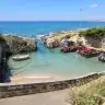 Il porticciolo di Torre Suda tra gli scogli, con l'acqua chiara e la costa verso nord