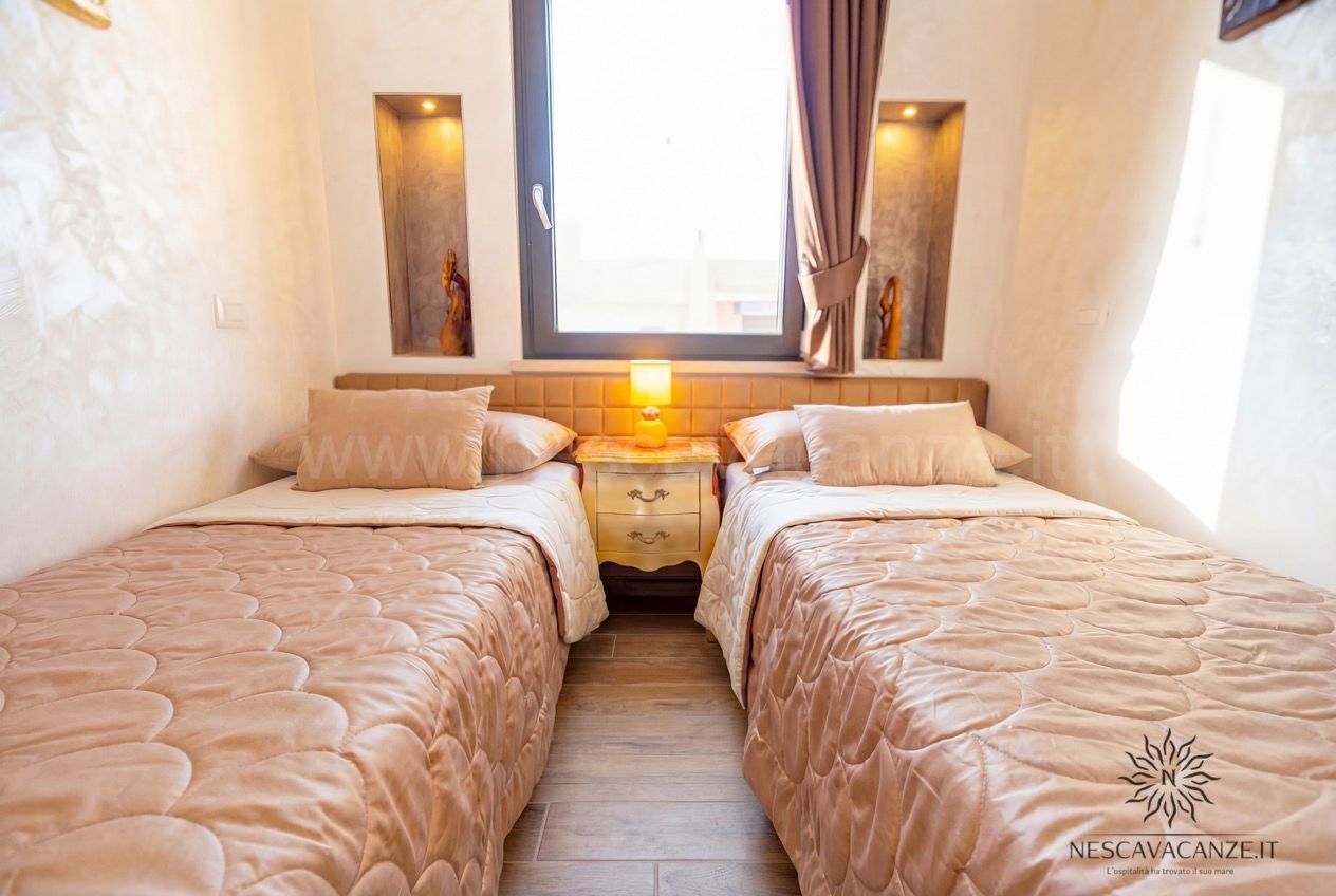Casa Giglio - camera con due letti singoli, comodino, lampada e finestra luminosa