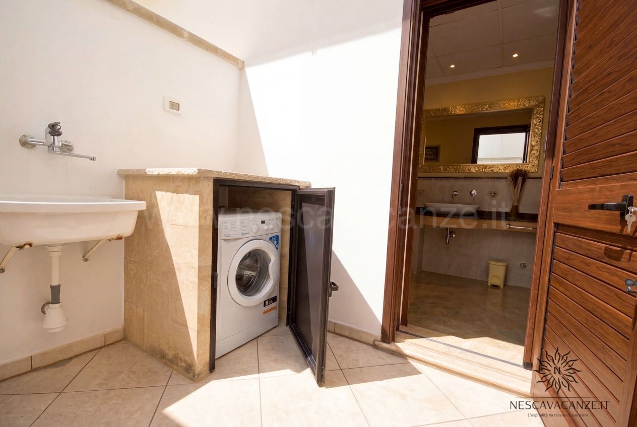 Casa Pescoluse 9 - zona lavanderia con lavatrice, lavabo e vista sul bagno