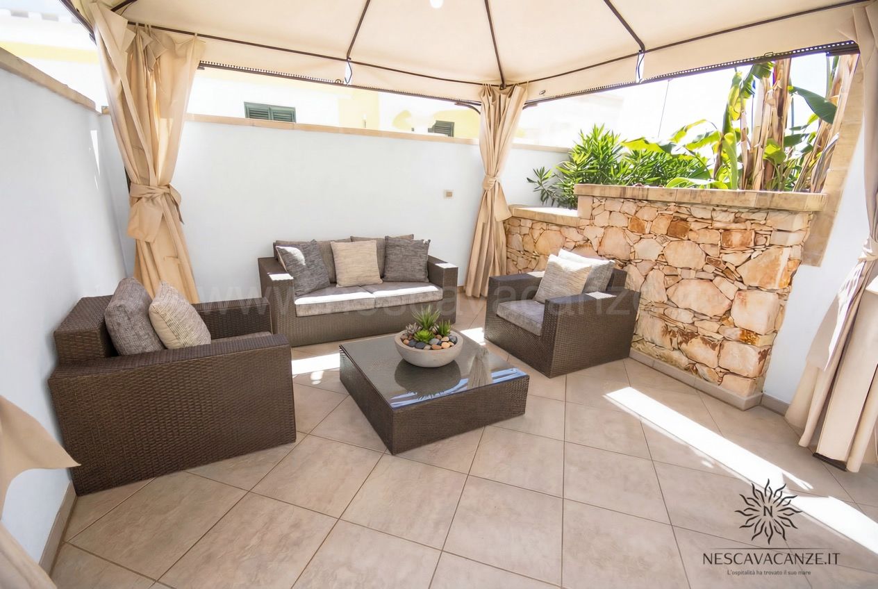 Casa Pescoluse 9 - terrazza lounge con divani in rattan, gazebo, parete in pietra e piante