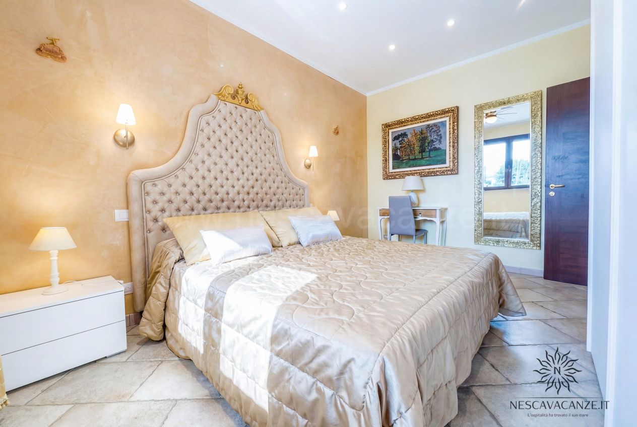 Casa Pescoluse 8 - Camera matrimoniale con letto capitonné, specchio dorato e scrittoio angolare