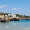 Gli scogli bassi e il mare calmo di Santa Caterina, visti dalla spiaggetta