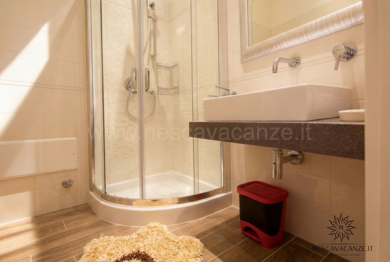 Casa Dune - bagno con doccia angolare, lavabo rettangolare e specchio incorniciato