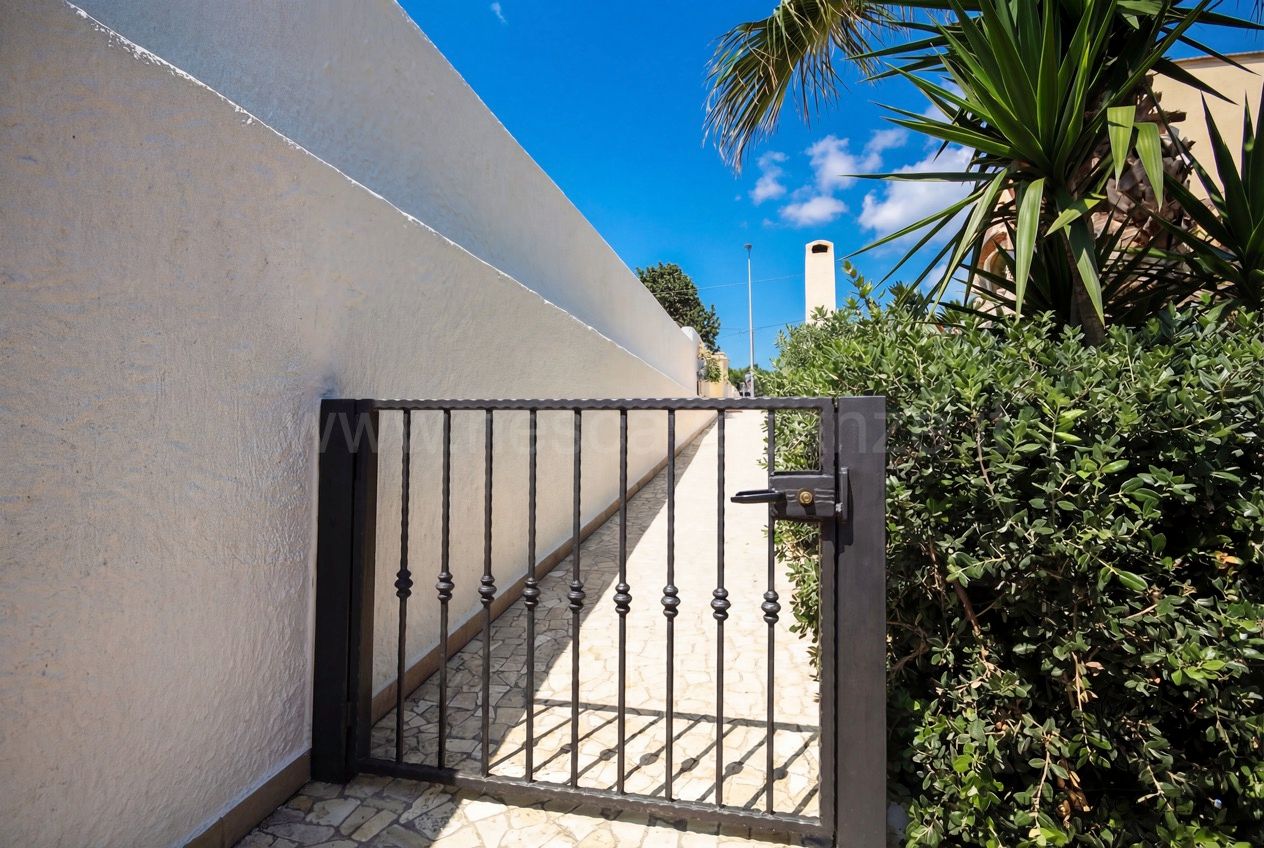 Casa Pescoluse 3 - cancelletto pedonale in ferro battuto lungo il vialetto laterale in pietra tra muro e siepe