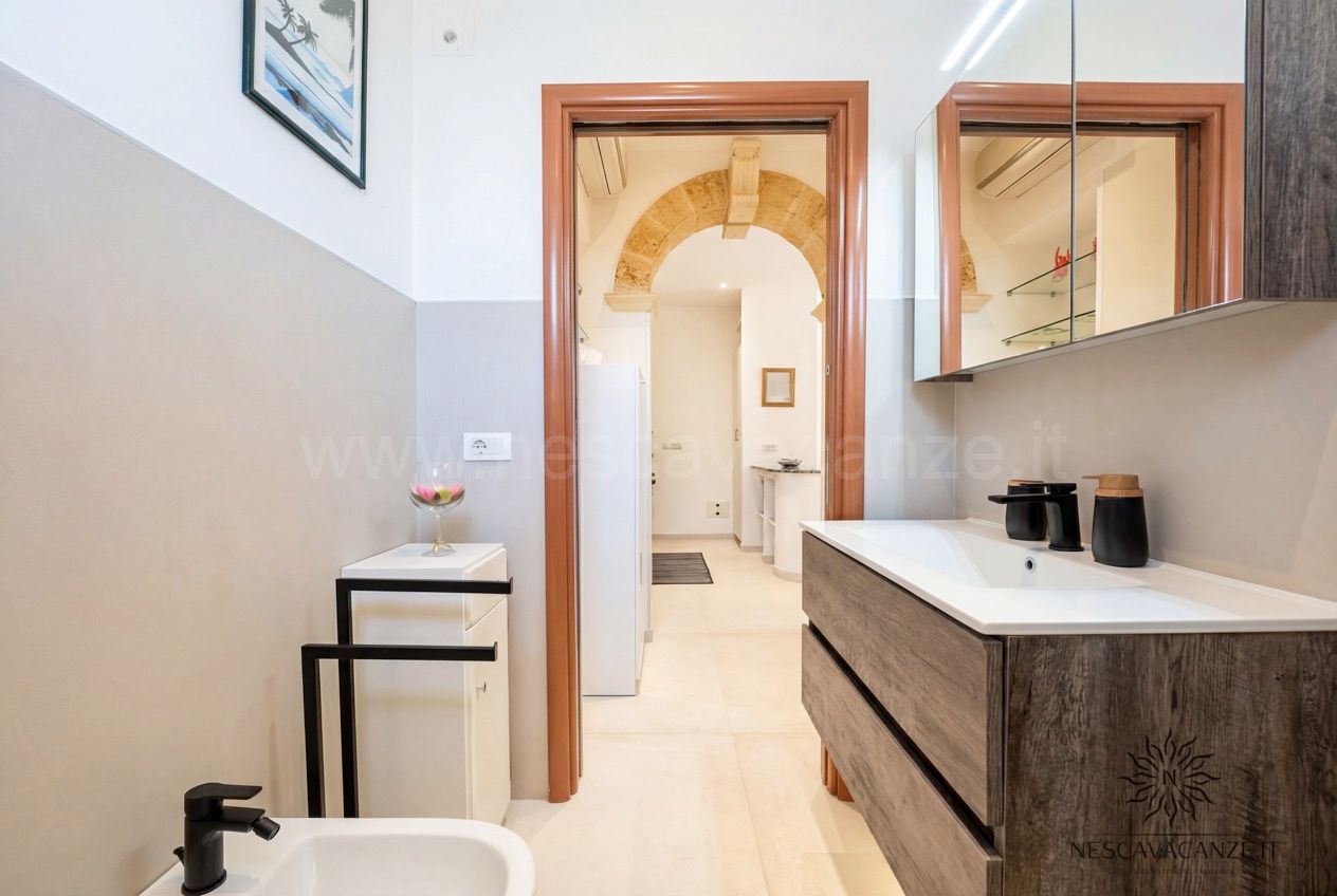 Casa Pescoluse 3 - bagno con doppio lavabo su mobile in legno, specchio, bidet e wc, vista sul corridoio ad arco