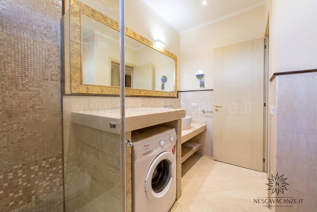 Casa Pescoluse 7 - bagno con doccia a mosaico, lavatrice e lavabo su mensola in pietra