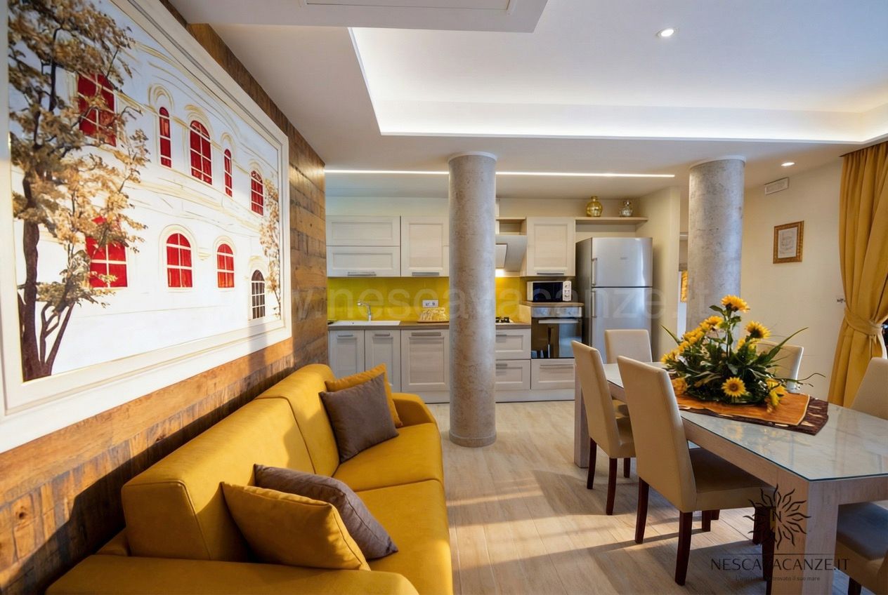 Casa Salento - soggiorno e cucina open space con divano giallo, colonne e quadro con finestre rosse