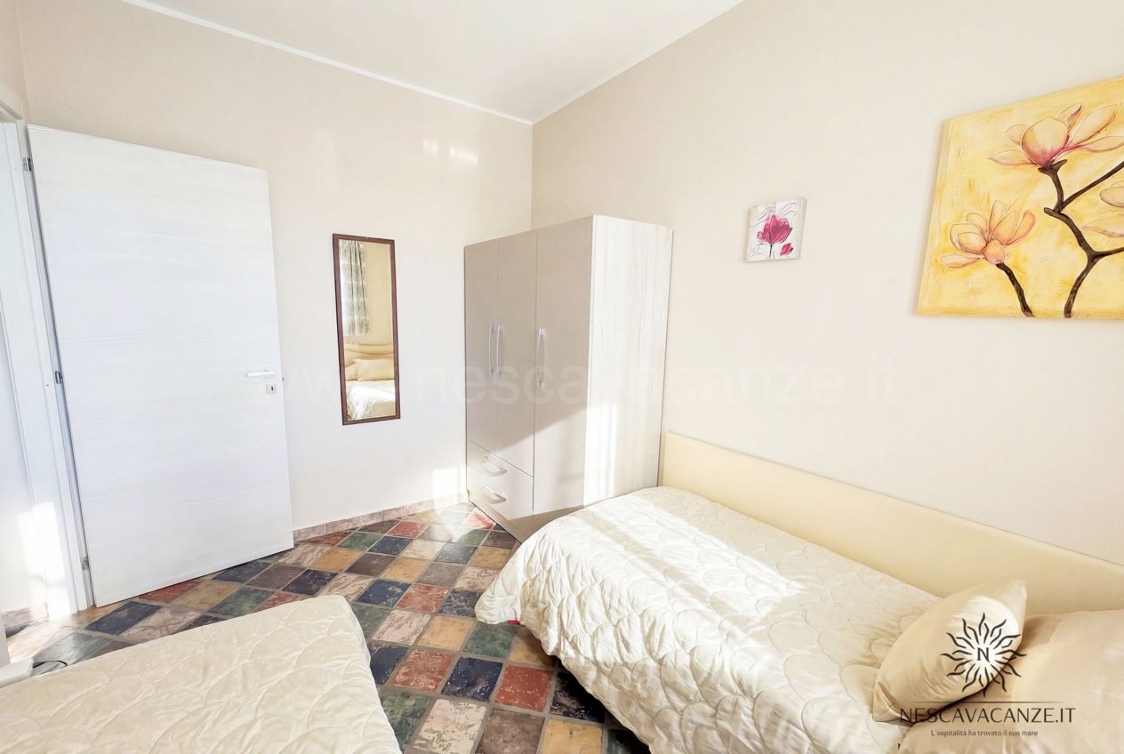 Casa Sabbia Oro - camera con letti singoli, armadio, specchio e quadro floreale giallo