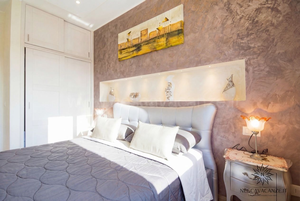 Casa Giglio - camera matrimoniale con parete decorata, quadro, comodini e lampade
