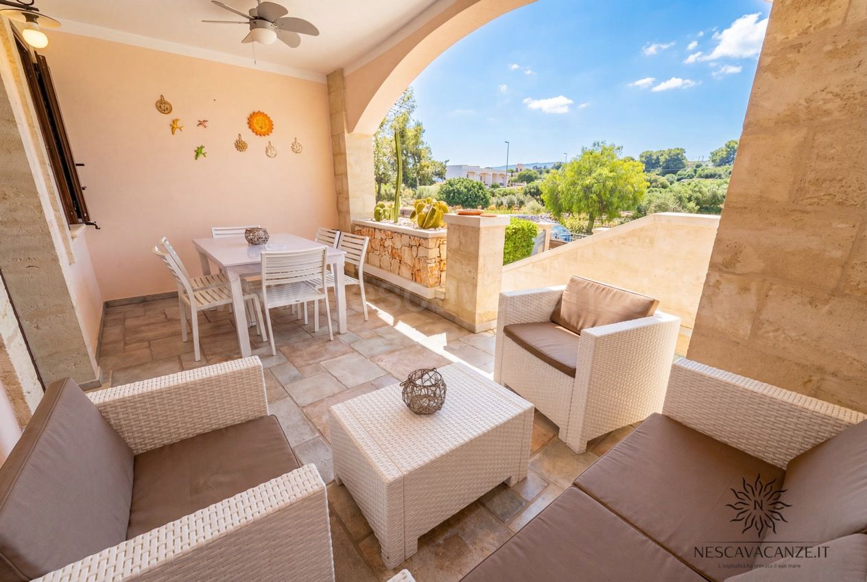 Casa Pescoluse 5 - veranda coperta con divani e poltrone in rattan, tavolo e vista panoramica