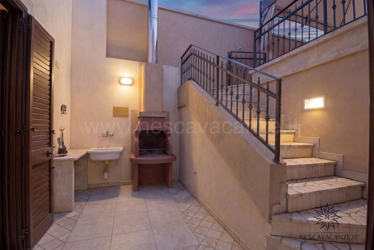 Casa Pescoluse 9 - corte esterna al tramonto con barbecue, lavabo e scala in pietra illuminata