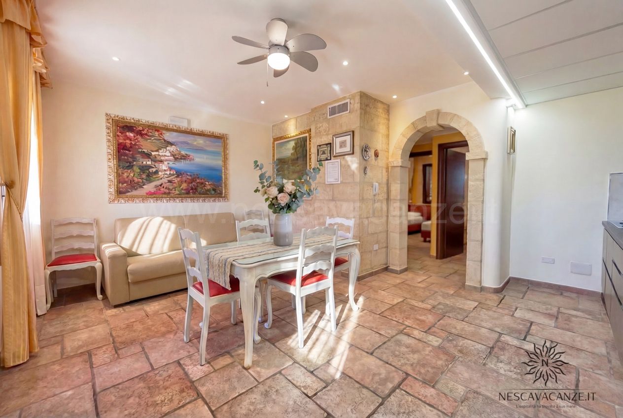 Casa Pescoluse 5 - soggiorno con divano, tavolo da pranzo, quadri e arco in pietra