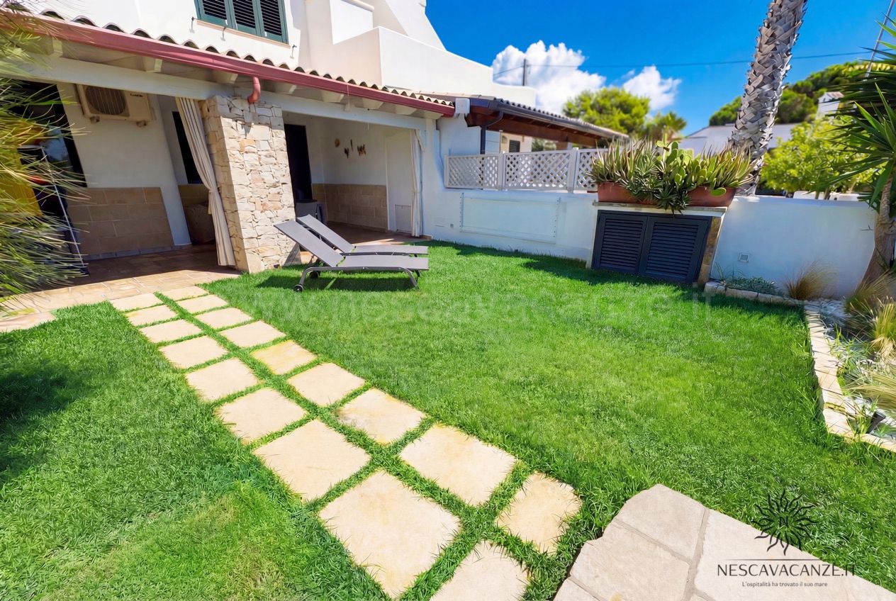 Casa Sabbia Oro - giardino con prato verde, camminamento in pietra e lettino prendisole