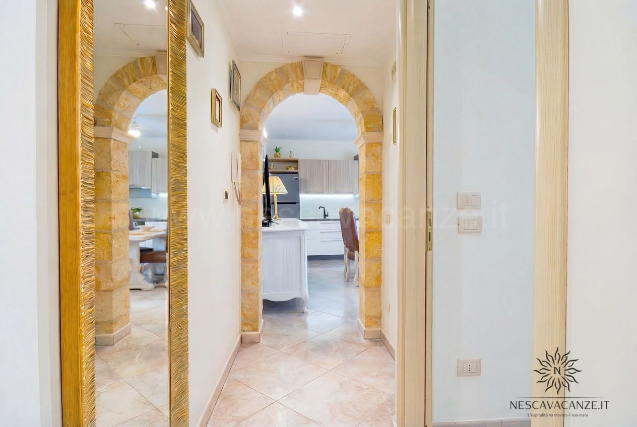 Casa Pescoluse 7 - corridoio con specchiere dorate, archi in pietra e vista sulla cucina