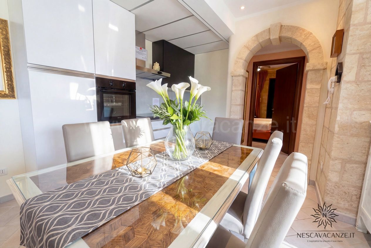 Casa Pescoluse 4 - tavolo da pranzo in vetro con calle, angolo cottura e arco in pietra sul corridoio