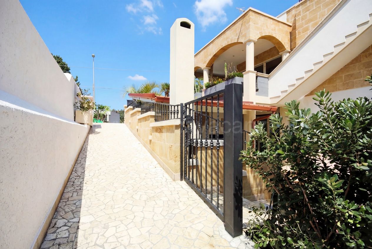 Casa Pescoluse 2 - vialetto in pietra con cancello e villa dal loggiato ad archi in tufo