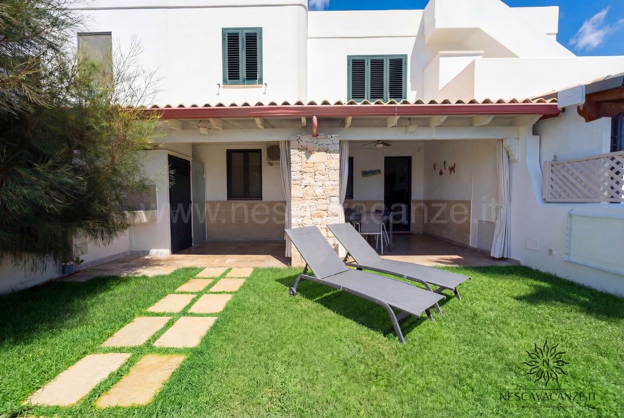 Casa Sabbia Oro - retro della casa con due lettini sul prato e veranda con pilastro in pietra