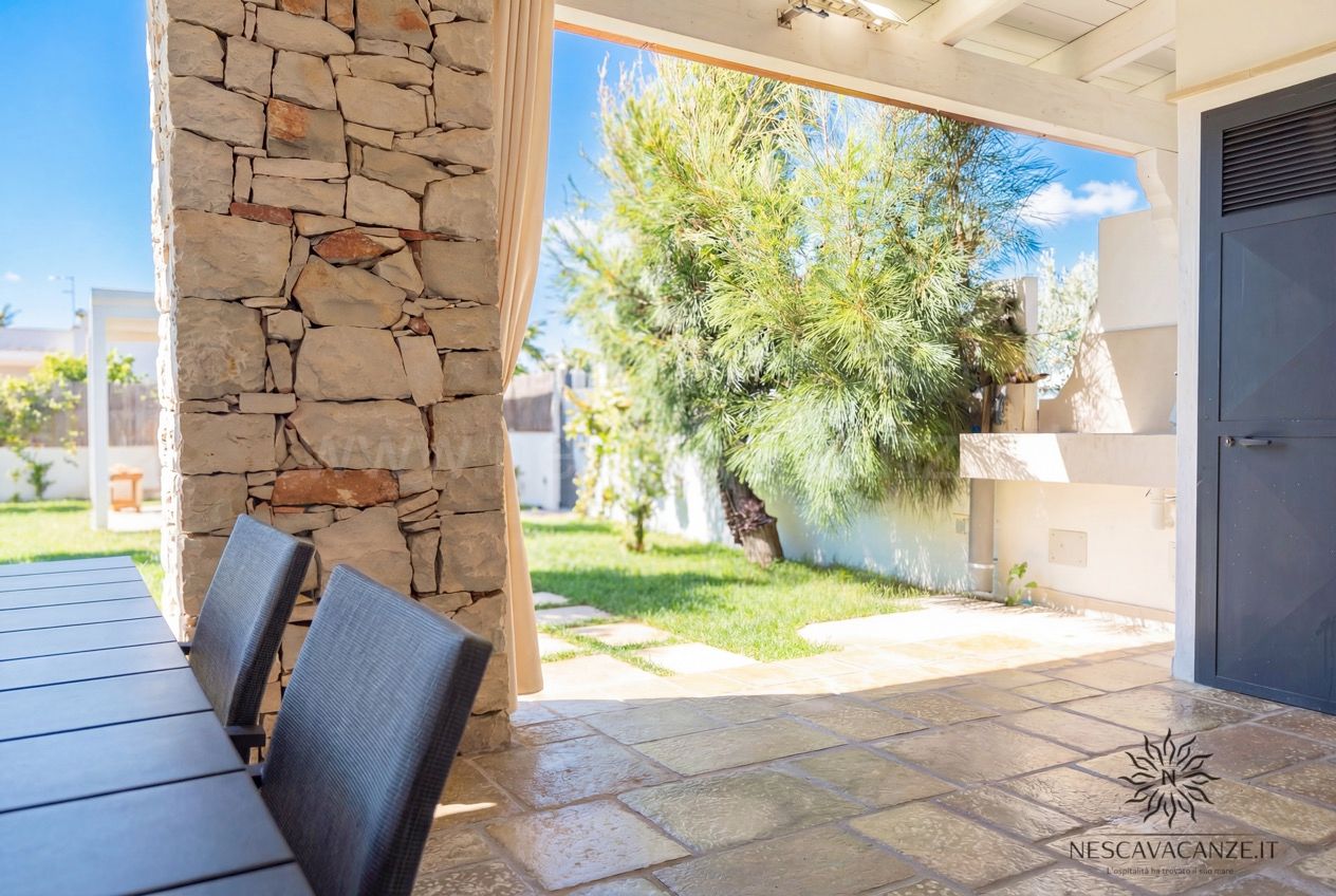 Casa Sabbia Oro - veranda con pilastro in pietra e vista sul giardino con pino e prato