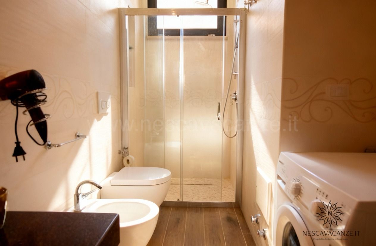 Casa Dune - bagno con doccia con box in vetro, wc, bidet e lavatrice. Fon appeso a muro