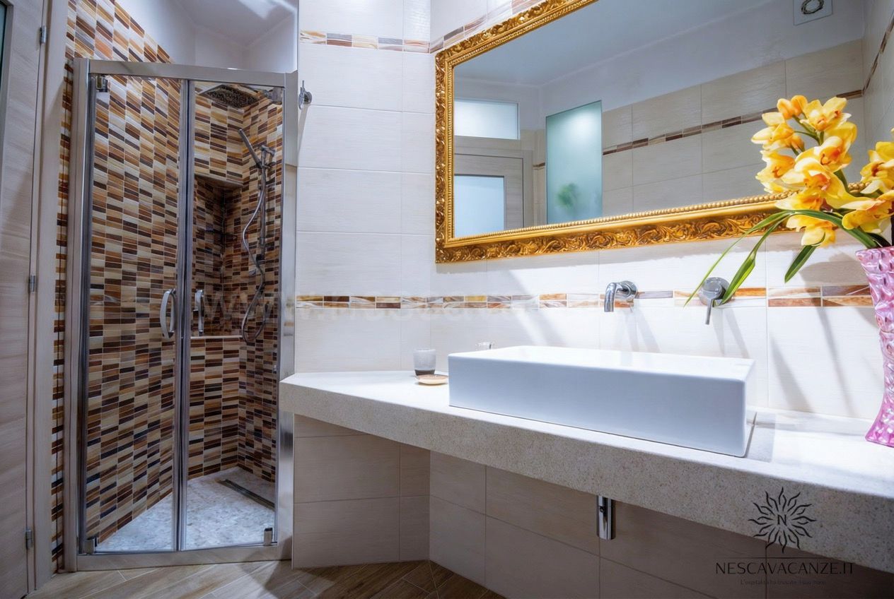Casa Salento - bagno con doccia rivestita a mosaico marrone, lavabo su piano e specchio dorato