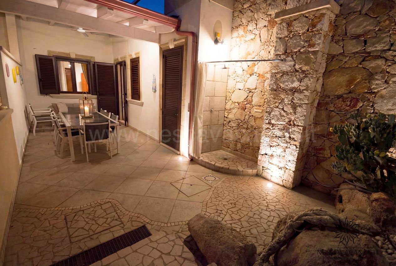 Casa Pescoluse 9 - corte notturna con doccia esterna in pietra, tavolo da pranzo e luci calde