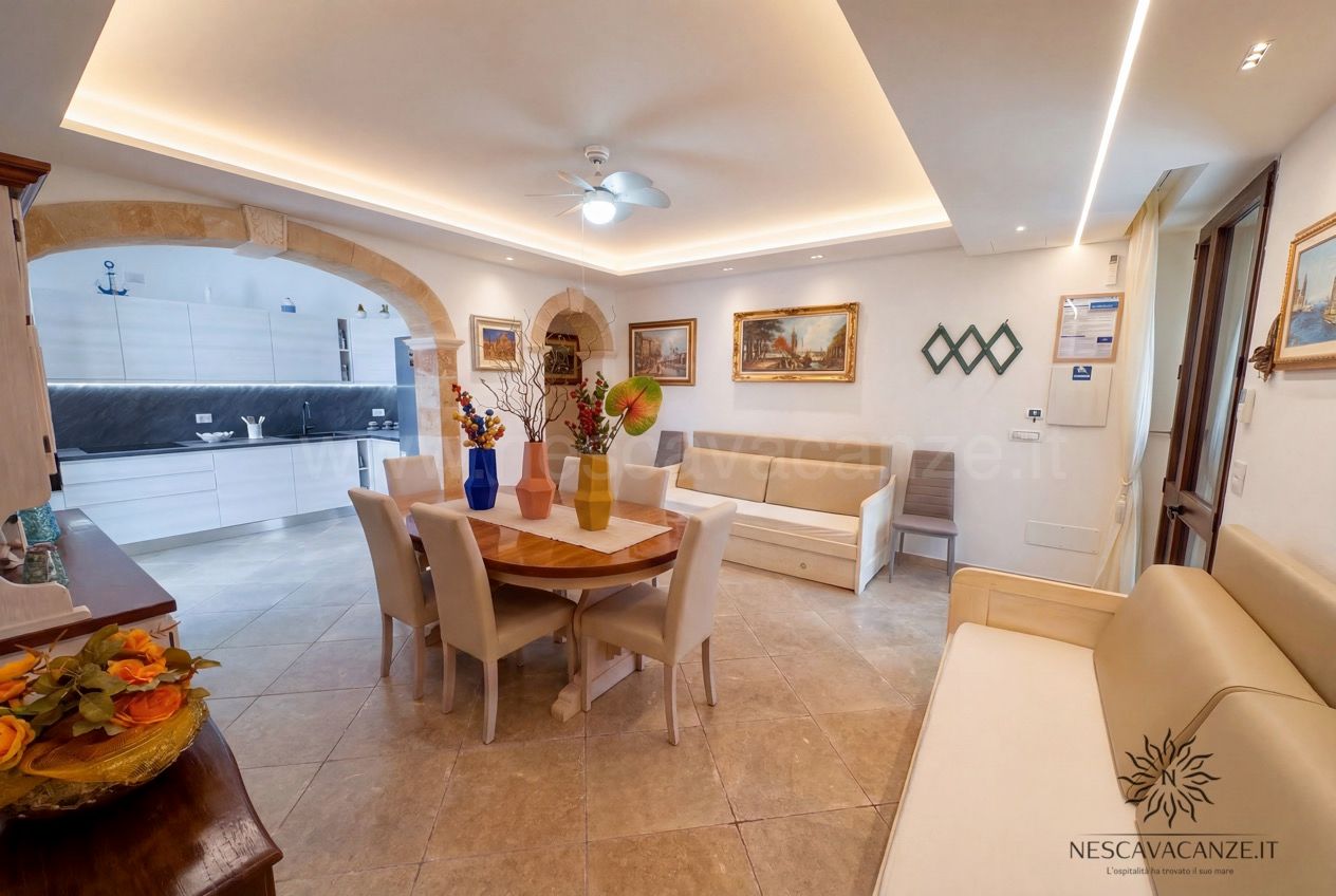 Casa Pescoluse 9 - open space soggiorno-pranzo con cucina, tavolo, divani, arco e quadri