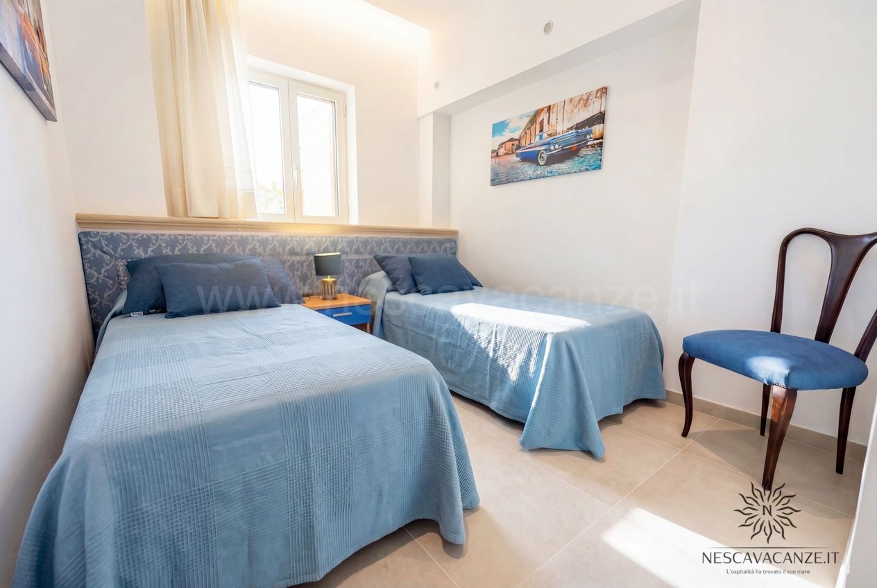 Casa Pescoluse 2 - camera con due letti singoli, copriletto azzurro, comodino e finestra