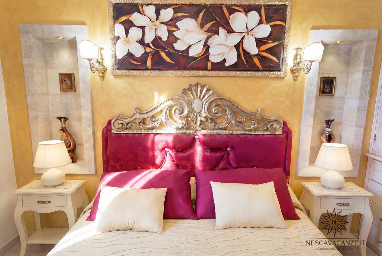 Casa Pescoluse 5 - dettaglio camera matrimoniale, testiera rossa intagliata e lampade sui comodini