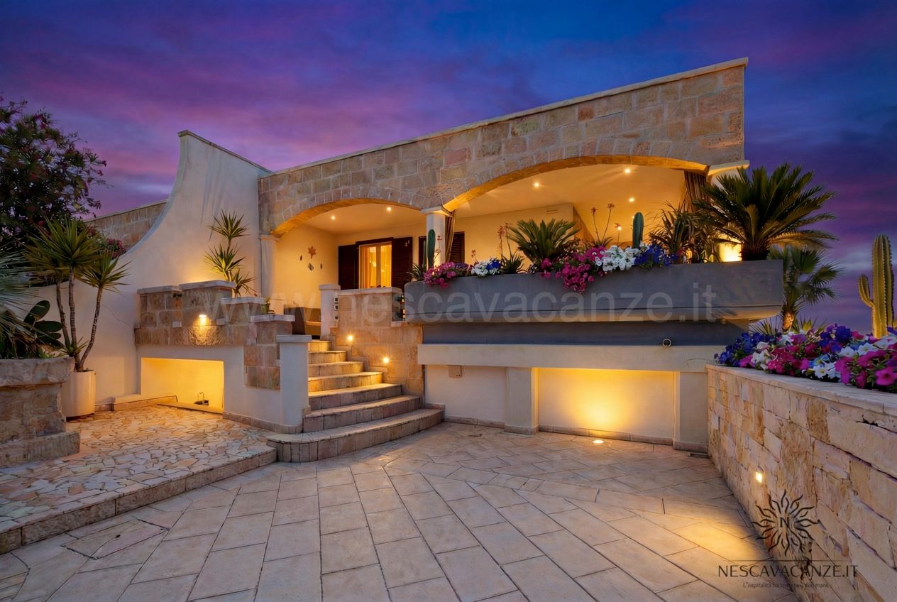 Casa Pescoluse 1 - cortile al tramonto con veranda illuminata, fiori e scala in pietra