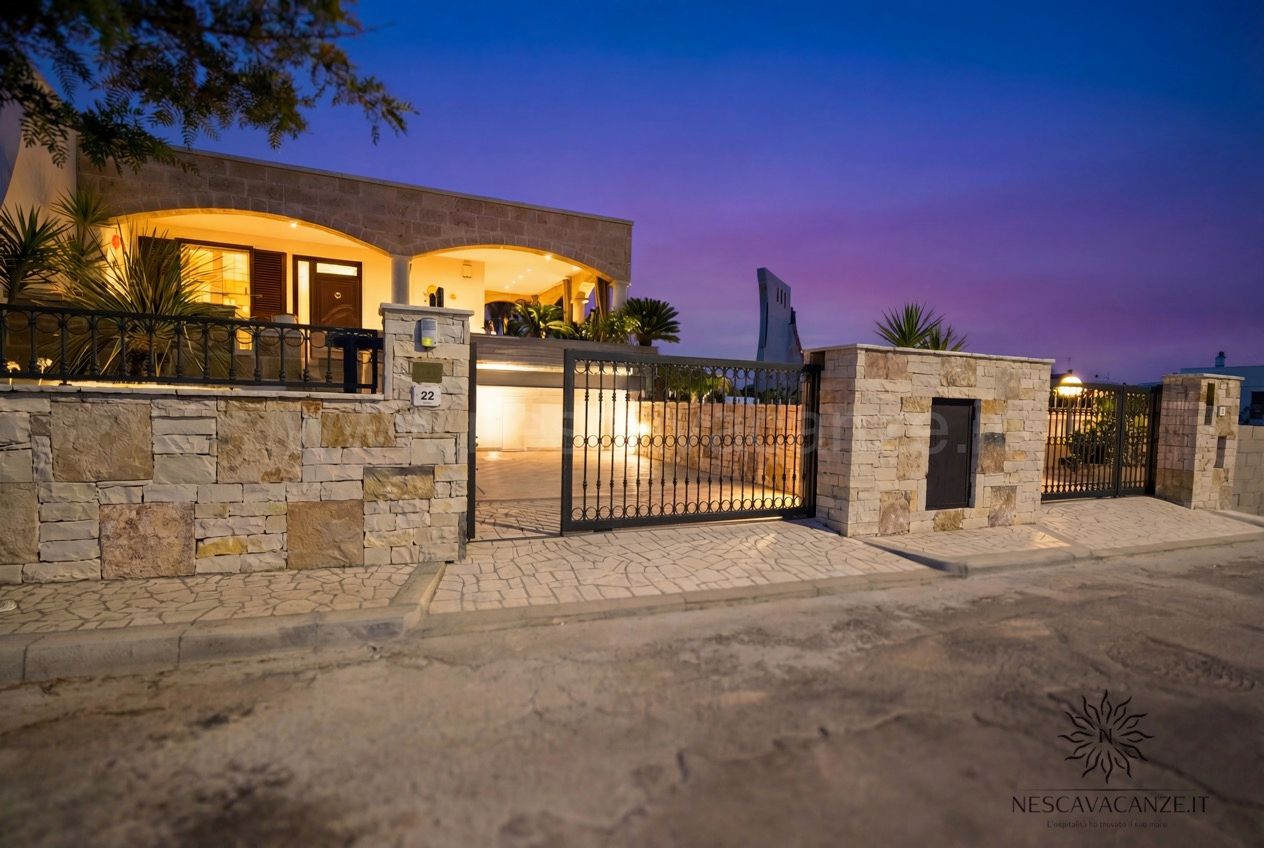 Casa Pescoluse 1 - facciata esterna al tramonto con villa illuminata e cancello in ferro