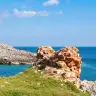 I resti della torre di Novaglie sulla scogliera, con una caletta di acqua turchese e il mare aperto