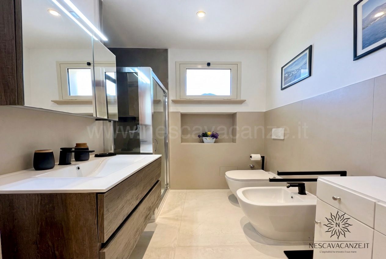 Casa Pescoluse 3 - bagno moderno con lavabo su mobile in legno, box doccia, wc e bidet, pareti beige e bianche