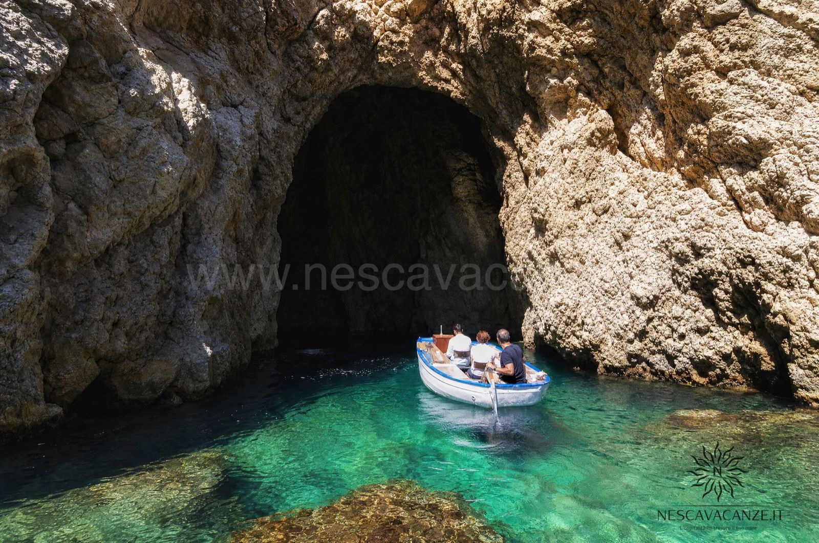 Barca all'ingresso di una grotta marina con acqua turchese lungo la costa adriatica del Salento, vicino a Castro