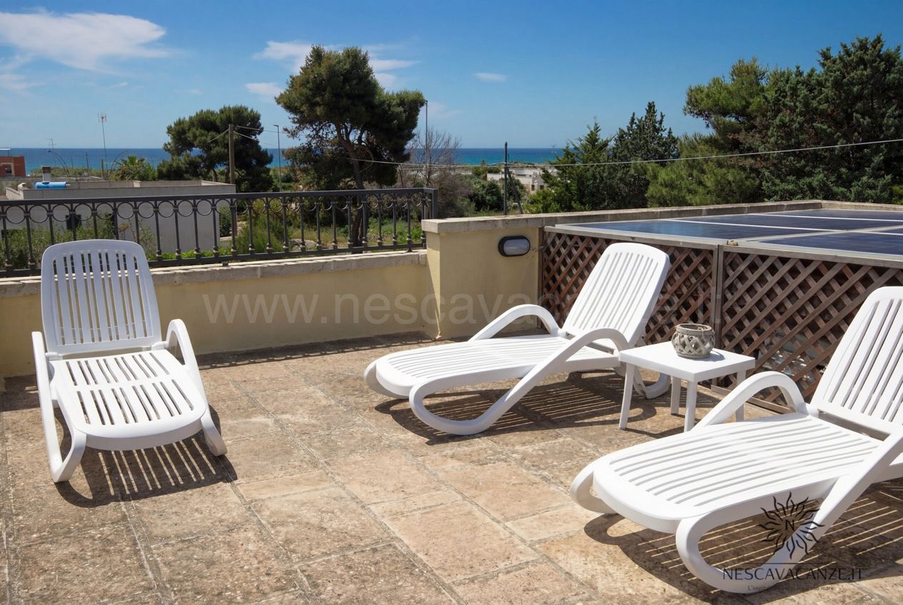 Casa Pescoluse 1 - terrazza sul tetto con lettini bianchi, vista mare e pannelli solari