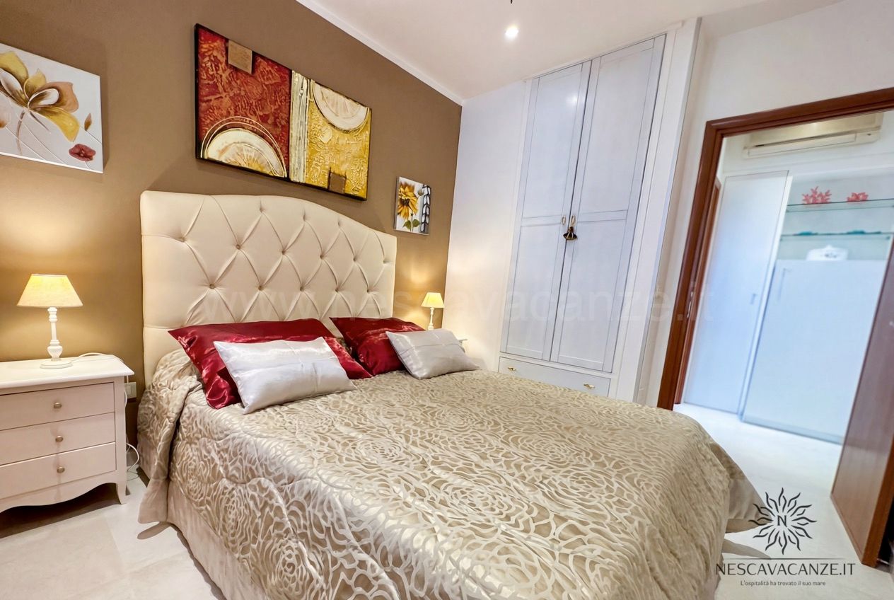 Casa Pescoluse 3 - seconda camera matrimoniale con testiera capitonné beige e armadio bianco a colonna