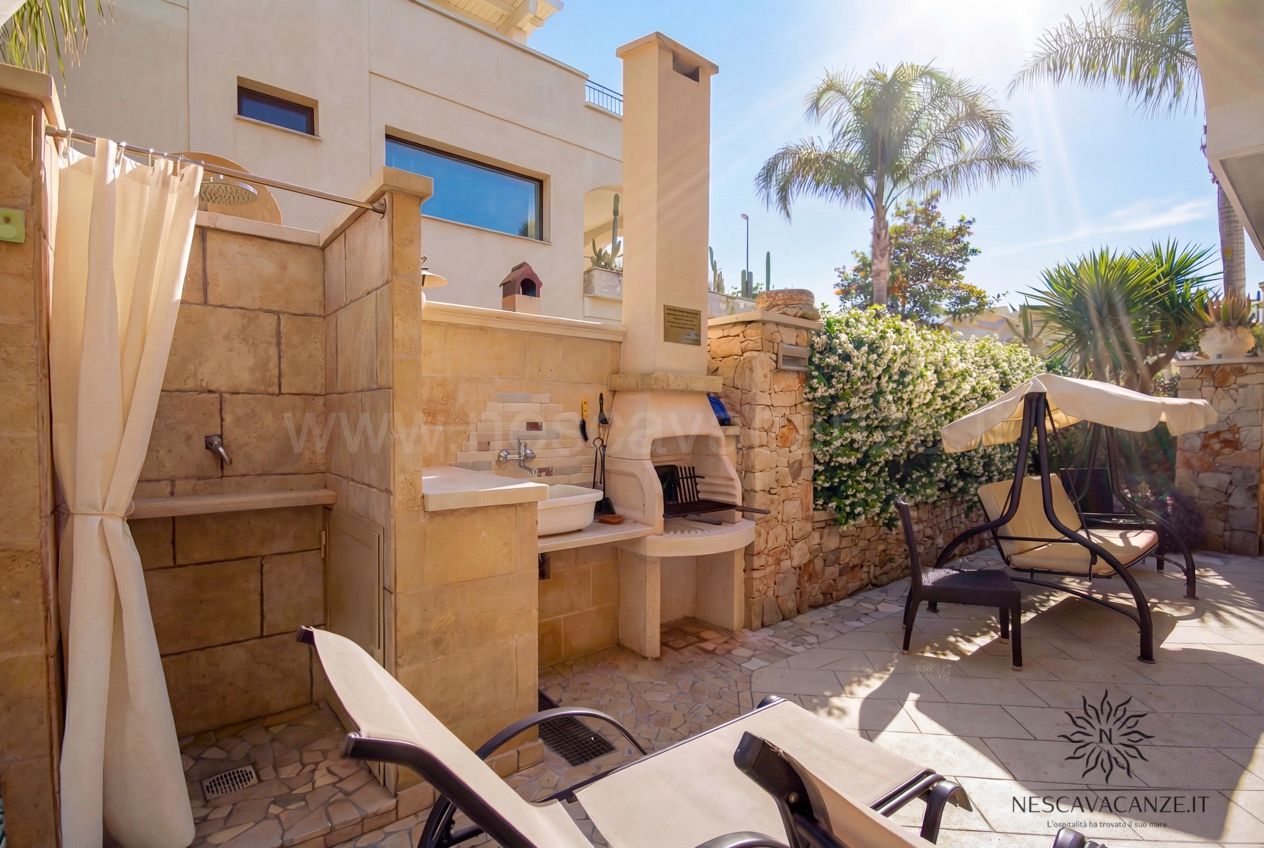 Casa Pescoluse 6 - zona esterna con cucina in muratura, lavabo, barbecue e doccia tra le palme