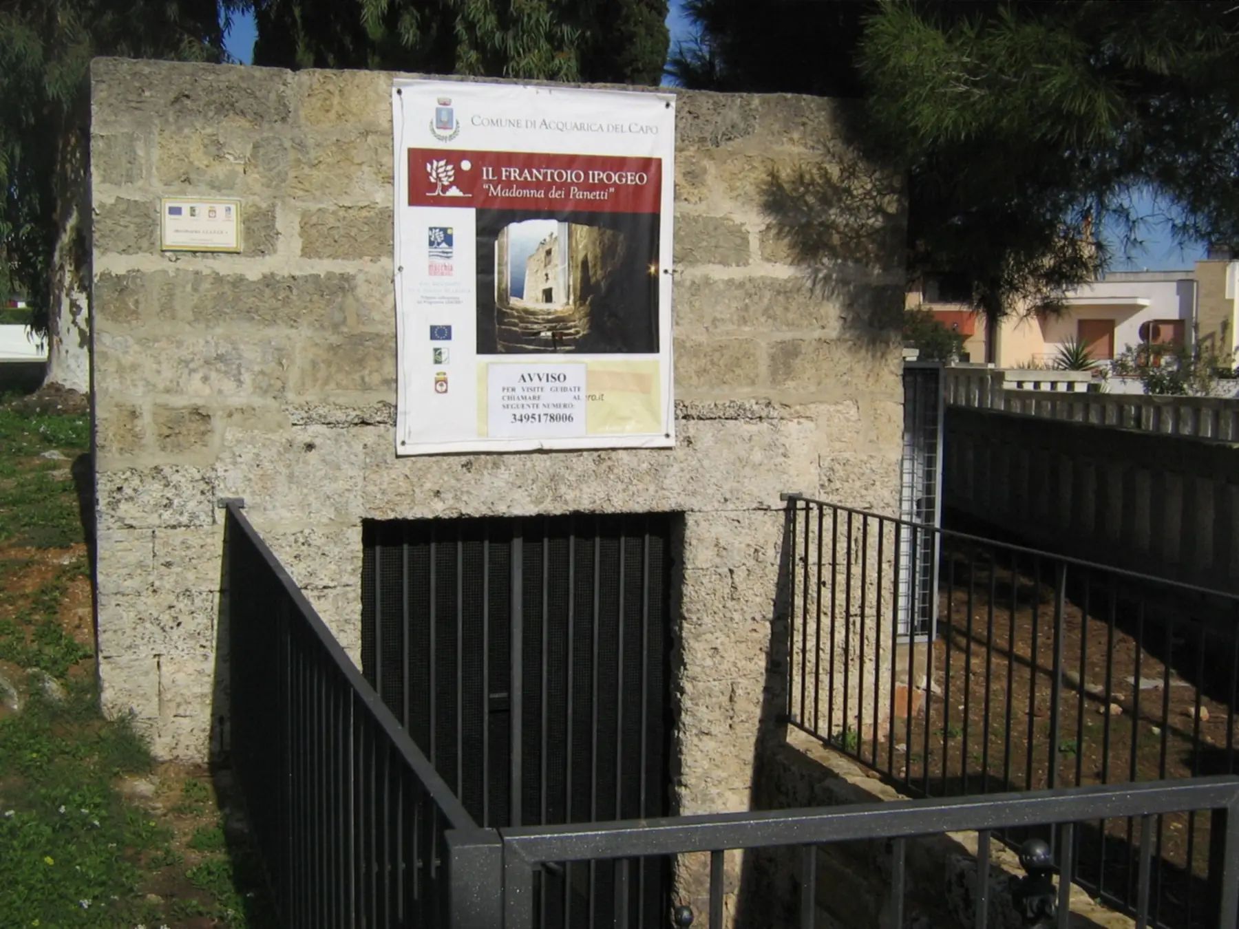 L'ingresso del frantoio ipogeo della Madonna dei Panetti ad Acquarica del Capo, con il cancello e il cartello del Comune