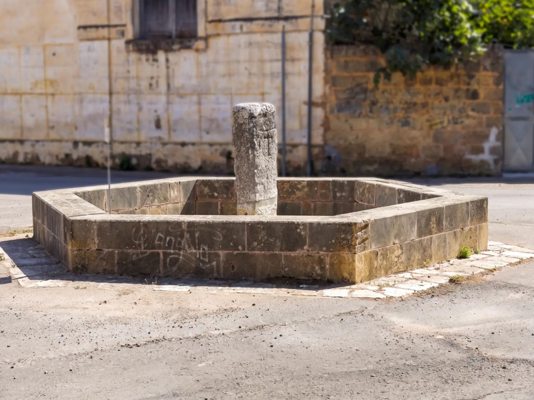 Il menhir del Foggiaro ad Arigliano, una colonna di pietra al centro di un recinto ottagonale, in una piazzetta