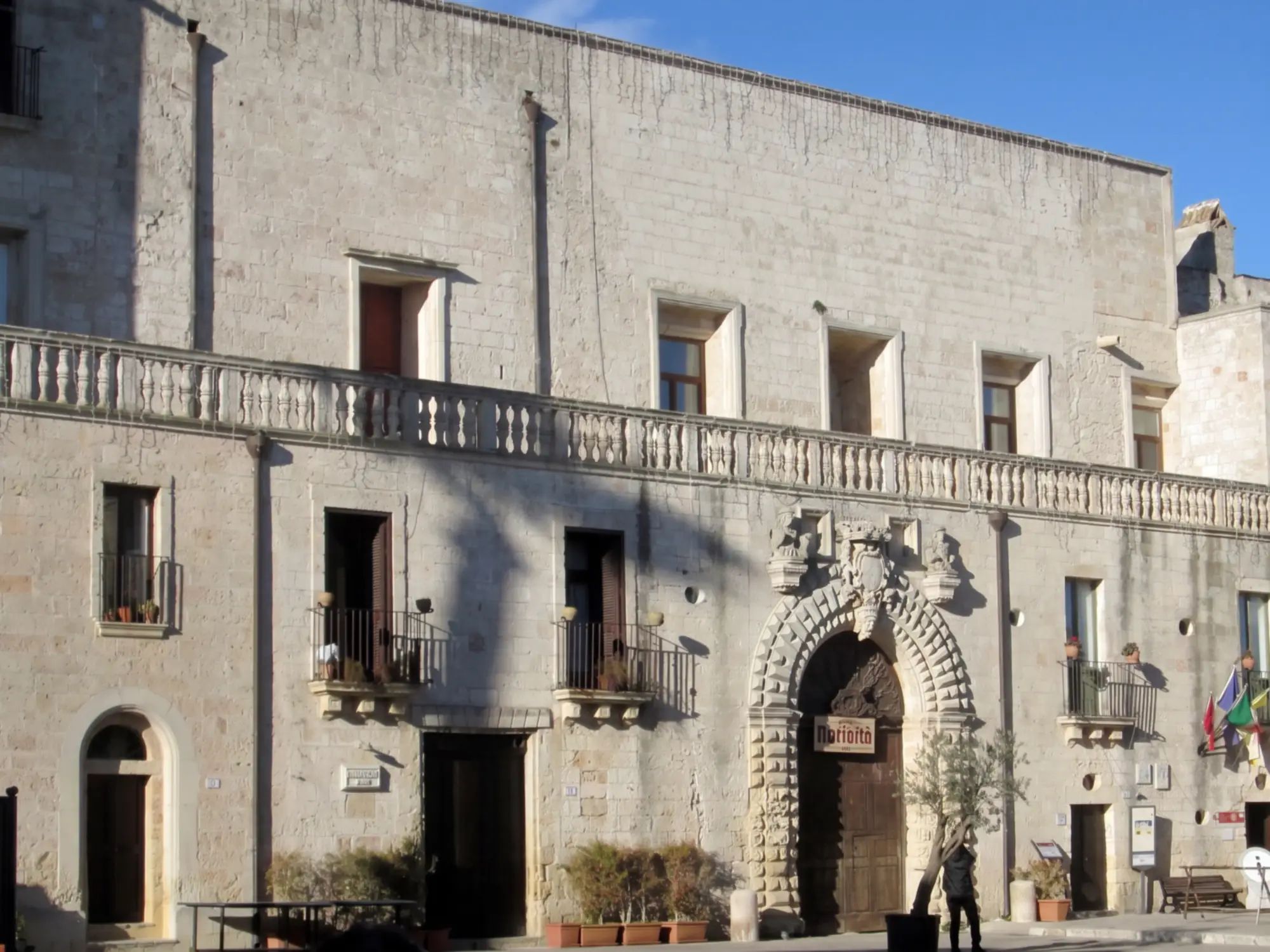 La facciata in pietra chiara di Palazzo Risolo a Specchia, con la balaustra lunga e il portale bugnato in piazza del Popolo