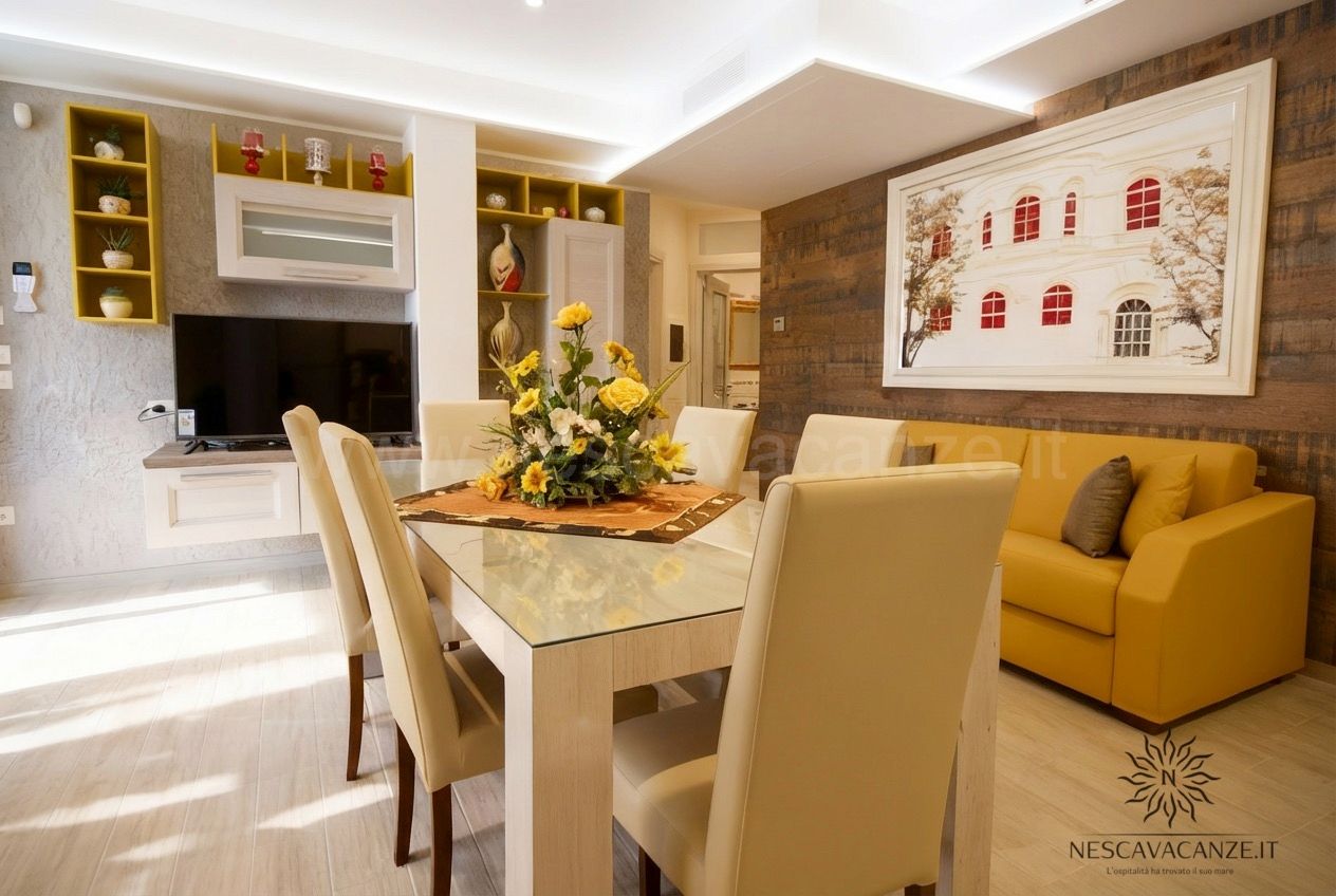 Casa Salento - soggiorno con tavolo in vetro e girasoli, divano giallo, mobile TV e quadro
