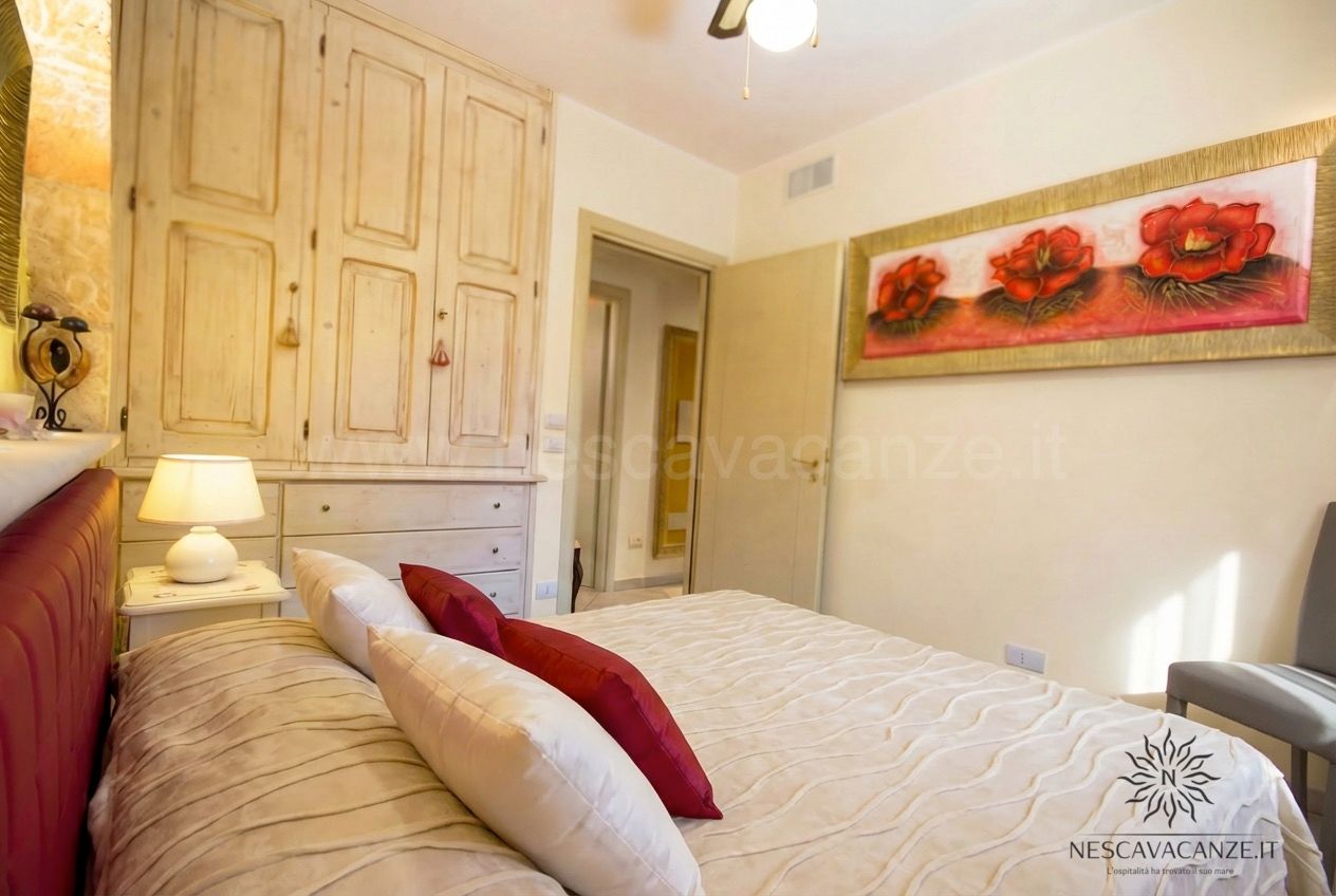 Casa Pescoluse 7 - camera matrimoniale con quadro floreale rosso, armadio e comodino