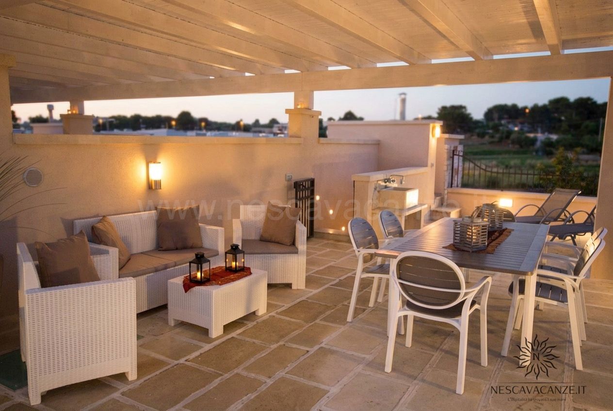 Casa Giglio - terrazzo di sera con divani in rattan bianco, tavolo e lanterne accese