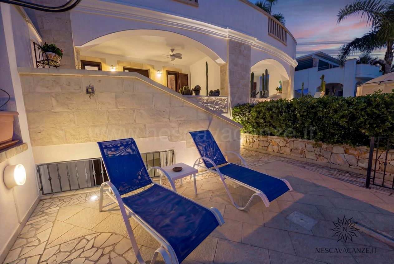 Casa Pescoluse 5 - patio al tramonto con lettini blu illuminati e scala in pietra